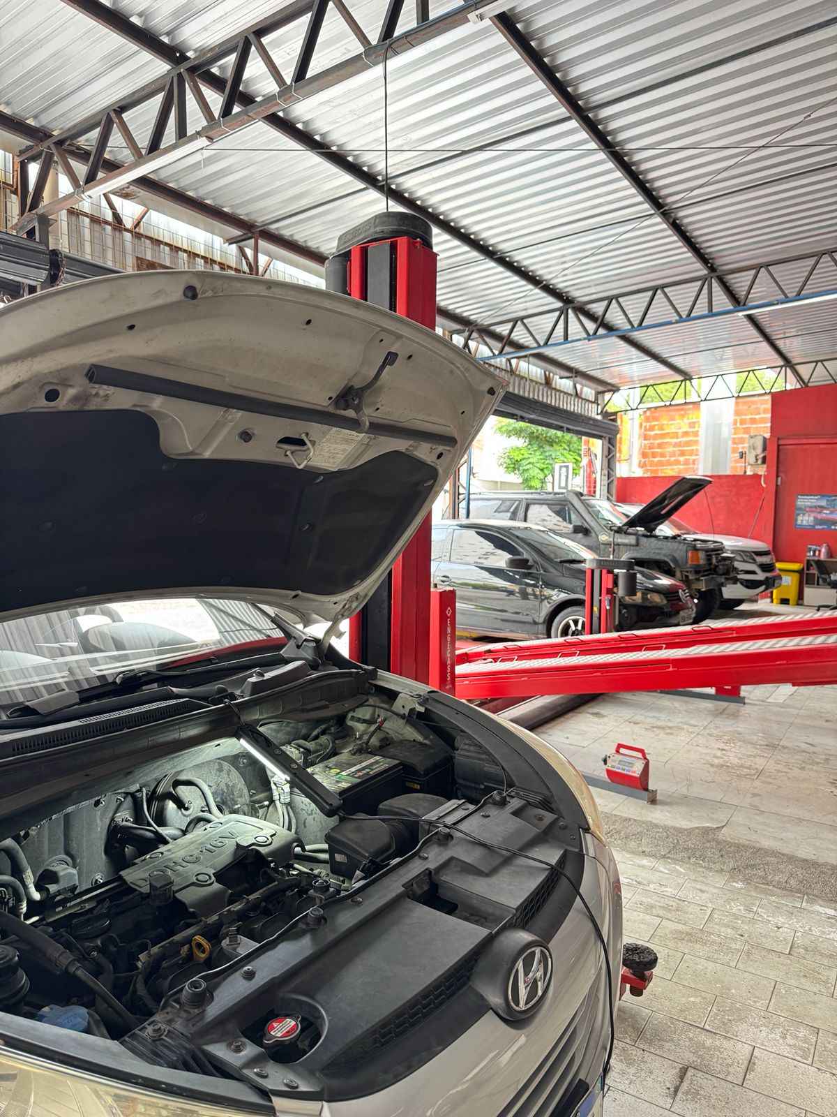 Área interna da oficina com elevador automotivo